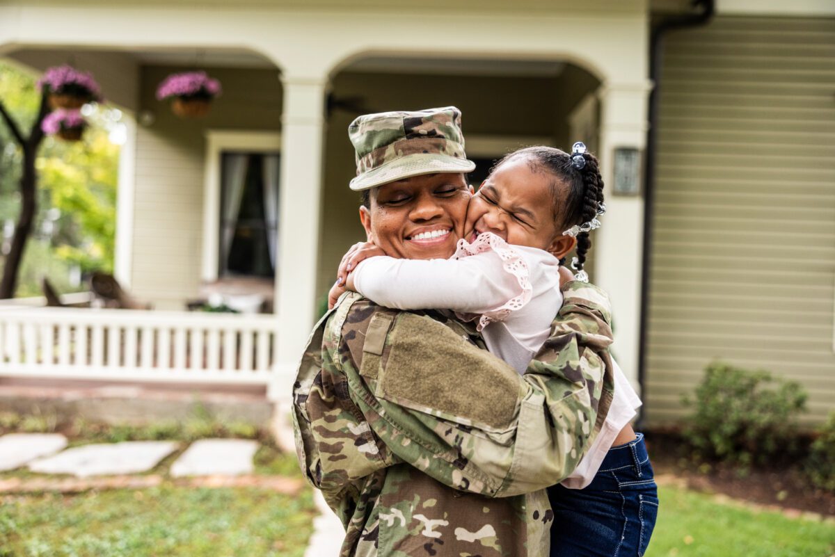 Man in military uniform embraces his daughter as he returns home from deployment